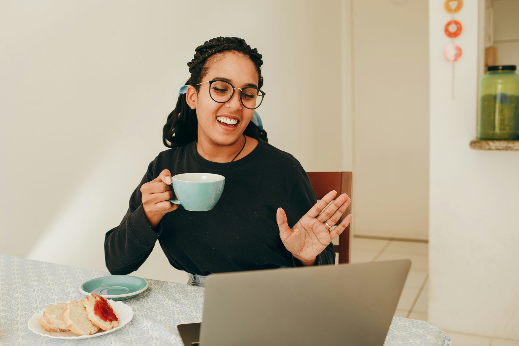 Woman smiling and waving during a telehealth counselling session on her laptop at home
