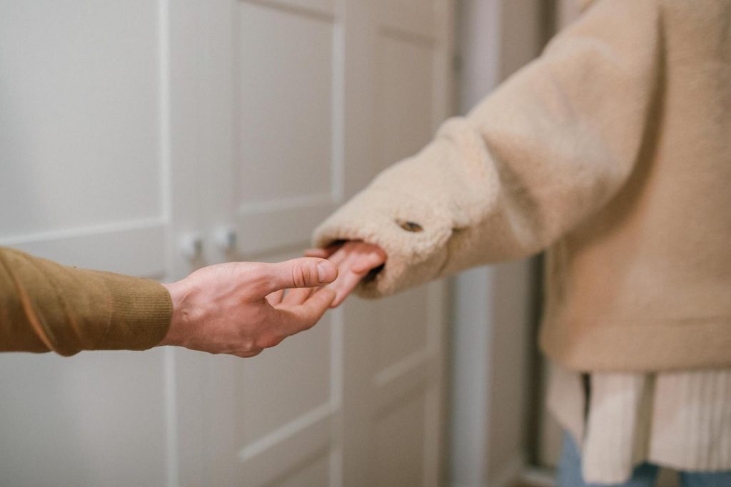 Two people holding hands, with one wearing a beige coat.