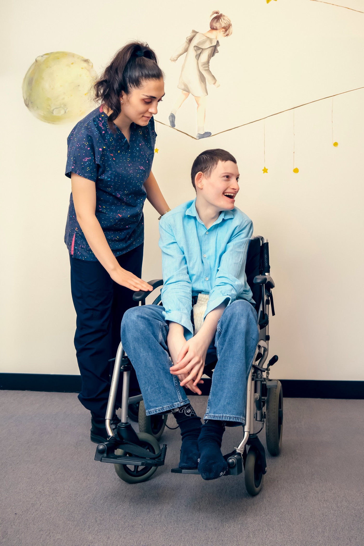 Smiling young man using a wheelchair with his support worker standing beside him