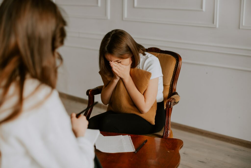 A woman is receiving Positive Behaviour Support through NDIS while sitting in a chair with a support worker sitting next to her.