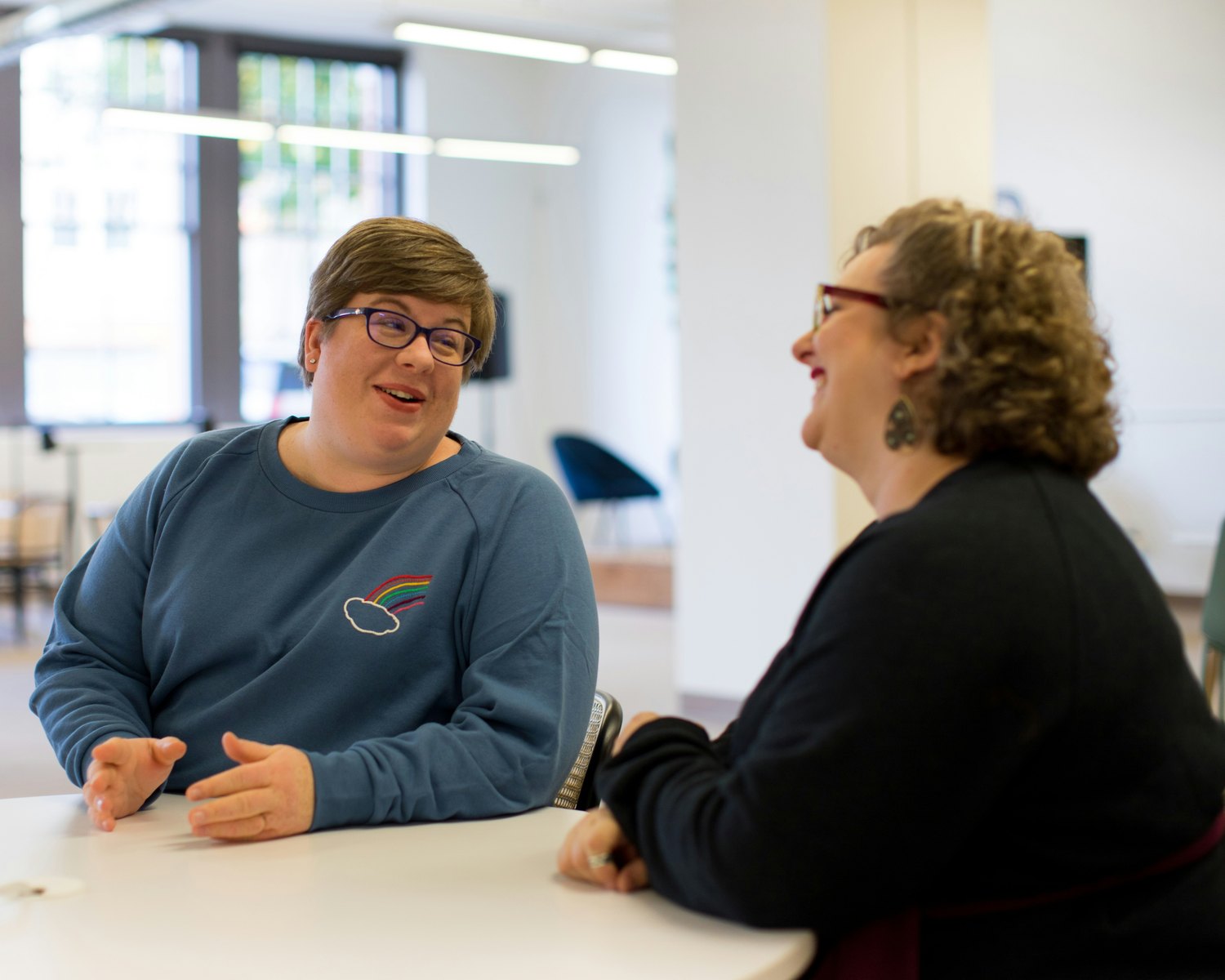Two people talking calmly at a table during a behaviour support planning conversation