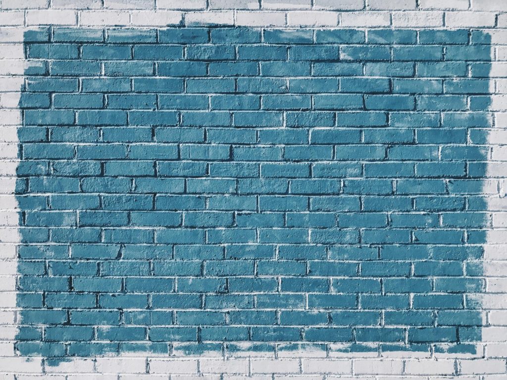 A white brick wall with a large rectangular section painted teal.
